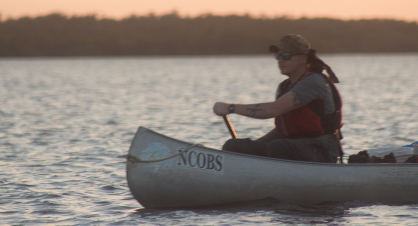 a person paddles a canoe on an outward bound veterans expedition